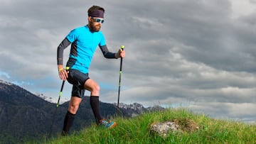 Un deportista sube una ladera con la ayuda de bastones para marcha nórdica.