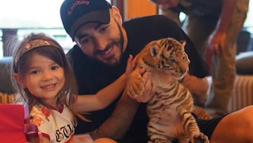 El futbolista franc&eacute;s Karim Benzema con una cr&iacute;a de tigre en brazos y su hija Melia al lado.