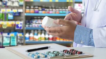 Imagen de un farmacéutico sosteniendo un bote de pastillas.