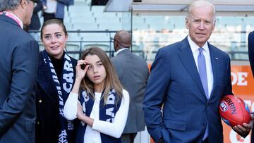 Joe Biden posa con un balon de fútbol americano antes de un partido en la Australian Football League.