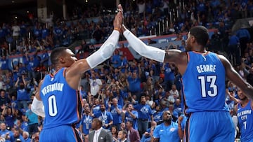 Russell Westbrook y Paul George se saludan con Carmelo Anthony al fondo.