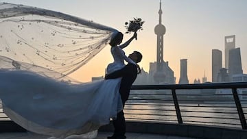 A couple poses for a wedding photo shoot on the Bund promenade along the Huangpu River during sunrise in Shanghai on September 7, 2022. (Photo by HECTOR RETAMAL / AFP) (Photo by HECTOR RETAMAL/AFP via Getty Images)