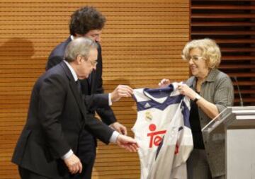 Manuela Carmena recibe una camiseta de manos de Sergio Llull y Florentino Pérez. 