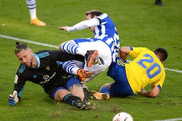 El duelo entre el Cádiz y la Real Sociedad, disputado en el Ramón de Carranza, dejó imágenes tan espectaculares como esta, en la que el portero argentino del conjunto amarillo, Jeremías Conan Ledesma, pugna por un balón con Monreal. El Triunfo por la mínima de los donostiarras les permite seguir liderando la tabla en solitario.