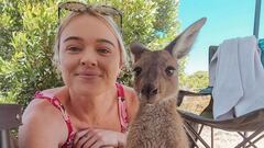 La surfista y activista Tash Peterson posando con un canguro con un arbusto y una silla detr&aacute;s. 