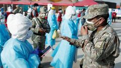 A soldier talks to a healthcare worker wearing personal protective equipment (PPE) at Cantagallo, an indigenous Shipibo-Conibo community, before the kick off of the vaccination campaign against the coronavirus disease (COVID-19), in Lima, Peru February 19, 2021. REUTERS/Angela Ponce