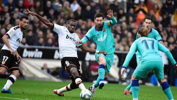 TOPSHOT - Valencia's Central African Republic-French midfielder Geoffrey Kondogbia (L) challenges Barcelona's Argentine forward Lionel Messi (C) during the Spanish league football match Valencia CF against FC Barcelona at the Mestalla stadium in