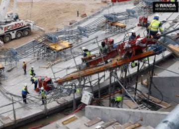 Mientras el anillo de tracción inferior de la cubierta permanece colocado sobre la grada baja al fondo de la imagen, los operarios conectan los gatos con los cables radiales que servirán para su izado.