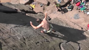 El escalador brit&aacute;nico Johnny Dawes probando de escalar Chalkstorm, en The Roaches (Reino Unido) sin la ayuda de las manos, solo con los pies, mientras varias personas se lo miran desde abajo. 