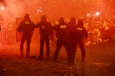 La policía antidisturbios tiene que intervenir en la avenida de los Campos Elíseos durante las celebraciones de la victoria del PSG en las calles de París.