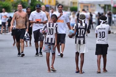 Jóvenes aficionados del Santos caminan con la camiseta número 10 antes de la presentación de Neymar.