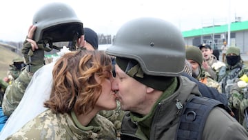 Members of the Ukrainian Territorial Defence Forces Lesia Ivashchenko and Valerii Fylymonov kiss at their wedding during Ukraine-Russia conflict, at a checkpoint in Kyiv, Ukraine March 6, 2022. REUTERS/Mykola Tymchenko