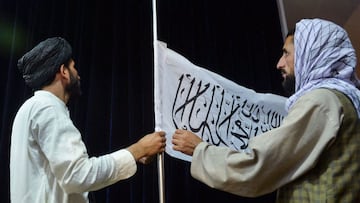 Men adjust the Taliban flag before the arrival of Taliban spokesperson Zabihullah Mujahid (unseen) to address the first press conference in Kabul on August 17, 2021 following the Taliban takeover of Afghanistan. 