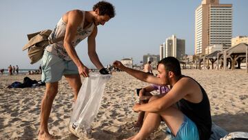 Julian Melcer collects a cigarette butt from a beach-goer as part of his environmental campaign at a beach in Tel Aviv, Israel April 20, 2021. Picture taken April 20, 2021. REUTERS/Amir Cohen