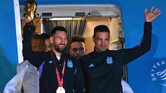 Argentina's captain and forward Lionel Messi (L) holds the FIFA World Cup Trophy alongside Argentina's coach Lionel Scaloni as they step off a plane upon arrival at Ezeiza International Airport after winning the Qatar 2022 World Cup tournament in Ezeiza, Buenos Aires province, Argentina on December 20, 2022. (Photo by Luis ROBAYO / AFP)