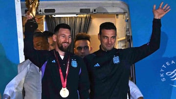 Argentina's captain and forward Lionel Messi (L) holds the FIFA World Cup Trophy alongside Argentina's coach Lionel Scaloni as they step off a plane upon arrival at Ezeiza International Airport after winning the Qatar 2022 World Cup tournament in Ezeiza, Buenos Aires province, Argentina on December 20, 2022. (Photo by Luis ROBAYO / AFP)