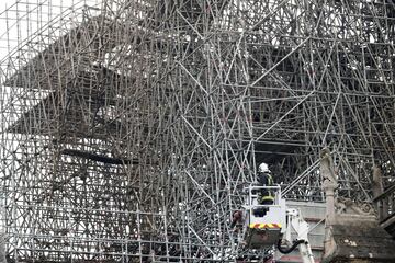 Un bombero trabaja en un elevador junto al andamiaje que cubre parte de la catedral de Notre Dame