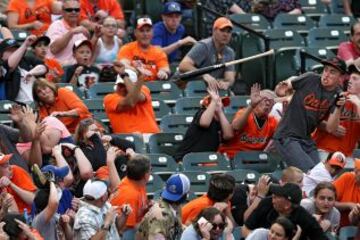 Los aficionados intentan esquivar el bate de Josh Donaldson de los Toronto Blue Jays en la tercera entrada contra los Baltimore Oriole