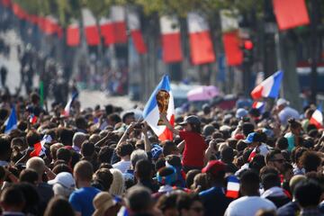 A child holds a placard shaped as a the World cup trophy as he waits with other supporters on the Champs-Elysees avenue in Paris on July 16, 2018, for the arrival of the French national football team for celebrations after France won the Russia 2018 World