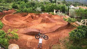 Teresa Fern&aacute;ndez-Miranda levanta su bici de BMX frente al campillo con saltos de tierra que se ha montado para entrenar durante el confinamiento en Castell&oacute;n.