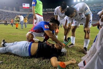 Jugadores de Alianza atienden a un aficionado herido tirado en la cancha luego de una estampida durante un partido de fútbol entre Alianza y FAS en el estadio Cuscatlán en San Salvador.