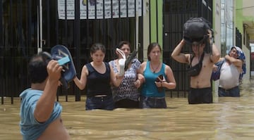 Residents cross a flooded street after rivers breached their banks due to torrential rains, causing flooding and widespread destruction in Piura, Peru, March 27, 2017.