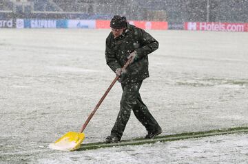 Un operario del club italiano retira la nieve de las lineas del terreno de juego.