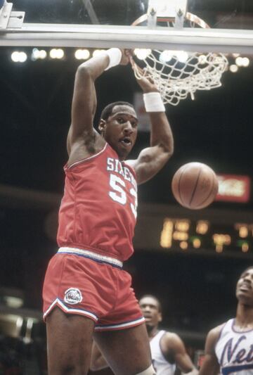 No fue un pívot históricamente dominante, aunque podría haberlo sido con más ética de trabajo por sus incuestionables facultades. Pero sí fue uno de los personajes más queridos y carismáticos de su época: Darryl Dawkins, Chocolate Thunder, era un 2,11 de 115 kilos que jugó en la NBA entre 1975 y 1989 y después pasó por Turín y Milán. Stevie Wonder le dio su apodo y él patentó unos mates tremendos a los que ponía nombre... y con los que rompió un tablero en 1979 y otro tres semanas después. El comisionado Larry O'Brien le dijo que se había un tercero se llevaría una suspensión y una multa de 5.000 dólares, y al final de esta temporada, la NBA cambió los aros y su unión con el tablero por un sistema más flexible que aceptaba mejor la tremenda presión que imprimía la llegada de un nuevo tipo de matadores. El siguiente que cobró fama por reventar aros fue, ya mucho después, Shaquille O'Neal. Dawkins solía decir que era un alienígena que venía del planeta Lovetron, donde practicaba junto a su pareja, Juicy Lucy, lo que llamaba interplanetary funkmanship. Al primer mate con el que reventó un aro lo llamó 'The Chocolate-Thunder-Flying, Robinzine-Crying, Teeth-Shaking, Glass-Breaking, Rump-Roasting, Bun-Toasting, Wham-Bam, Glass-Breaker-I-Am-Jam'. 