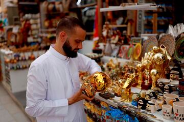 Cuando faltan ya sólo nueve días para el pistoletazo de salida, en las calles de Qatar se respira aroma de Mundial. En la imagen, un vendedor coloca sus objetos de merchandising del campeonato en los exteriores de su tienda, en un área de mercado en Doha. Todo el género luce reluciente, como si de oro se tratase.