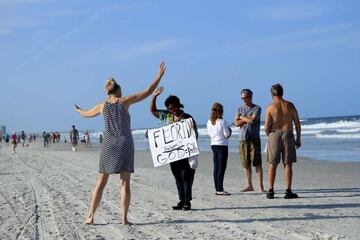 Una chica eleva sus brazos en una pequeña reunión de personas en Jacksonville Beach, Florida.