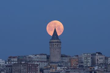 The moon is seen behind the Galata Tower in Istanbul, Turkey, March 14, 2025. REUTERS/Dilara Senkaya