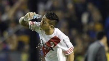 Argentina's River Plate forward Sebastian Driussi (R) and midfielder Leonardo Ponzio react after being pepper sprayed by Boca Junior supporters before the start of the second half of the Copa Libertadores 2015 second leg football match at the "Bombonera" stadium in Buenos Aires, Argentina, on May 14, 2015. The match was suspended. AFP PHOTO / JUAN MABROMATA