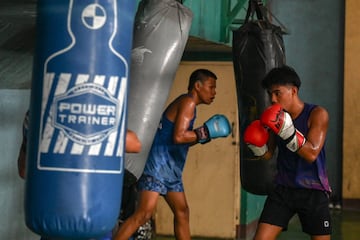 Varios j¨®venes entrenan a la vez con los sacos de boxeo.
