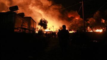 Migrants leave as a fire burns in the Moria camp on the island of Lesbos on September 9, 2020. (Photo by Manolis LAGOUTARIS / AFP)