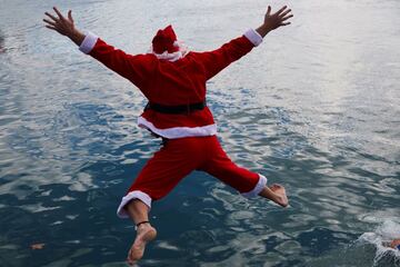 Un participante disfrazado de Papá Noel se lanza al agua para participar en la 111º edición de la Copa Nadal.