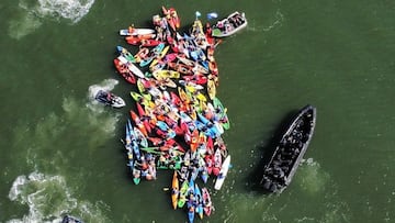 Kayakistas del grupo Rising Tide en el puerto de Newcastle (Australia), el sábado 25 de noviembre del 2023, rodeados por la policía.