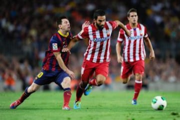 Arda Turan se lleva el balón ante Messi.