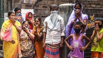 People protecting their faces stand looking as a man dressed up as Hindu deity of death Yamaraj to raise awareness about the coronavirus walks past during a government-imposed nationwide lockdown as a preventive measure against the COVID-19 coronavirus, i