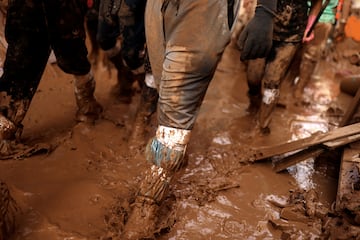 Los voluntarios caminan por una calle cubierta de barro mientras se preparan para ayudar tras las inundaciones provocadas por las fuertes lluvias en Paiporta, cerca de Valencia, España.