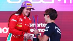 Marta García recibe un trofeo de la F1 Academy de manos de Russell.