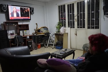 Una mujer observa la pantalla de un televisor público que transmite un reportaje tras las fuertes explosiones ocurridas en Caracas