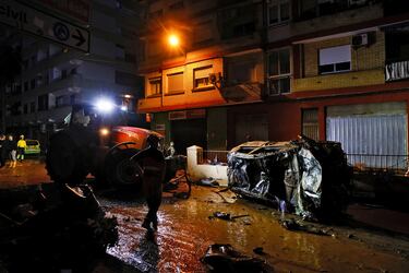 Un tractor retira un coche de la calle tras las lluvias torrenciales que provocaron inundaciones en Alfafar, Valencia.