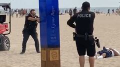 Dos polic&iacute;as apuntan a un hombre en el suelo que ha recibido varios disparos en Huntington Beach (California, Estados Unidos), el domingo 26 de septiembre del 2021, durante el US Open of Surfing. 
