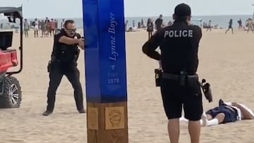 Dos polic&iacute;as apuntan a un hombre en el suelo que ha recibido varios disparos en Huntington Beach (California, Estados Unidos), el domingo 26 de septiembre del 2021, durante el US Open of Surfing. 