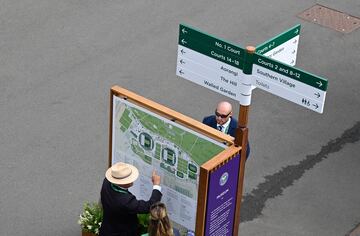 Los trabajadores de Wimbledon muestran las direcciones a seguir al público antes del comienzo del partido. 