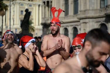 Participantes de la carrera a nado vestidos con gorros de Santa Claus o con cuernos de reno.