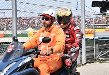 Francesco Bagnaia, del equipo Ducati Lenovo, abandona la pista en la parte trasera de una motocicleta tras sufrir un accidente en la carrera de MotoGP.