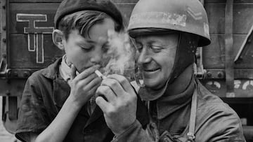 El cabo Fred Sicklong, un motociclista del XXX Cuerpo, 2.º Ejército británico enciende un cigarrillo para un joven francés en la ciudad liberada de Bayeux tras la Operación Overlord.