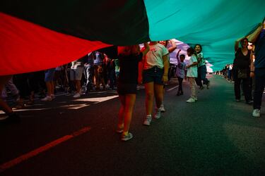 Decenas de personas extienden una bandera de Palestina durante una manifestación en apoyo a Palestina en Barcelona.