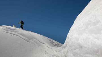 Un snowboarder y su perro suben por una montaña de nieve del Pirineo.